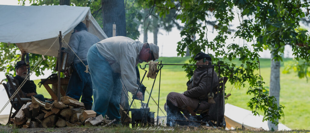 A Civil War soldier making coffee over a campfire, carefully pouring water into a pot. Dressed in a period-appropriate uniform, he focuses on his task, with the glow of the fire illuminating his face. The scene captures a moment of daily life and camaraderie among soldiers during the war.